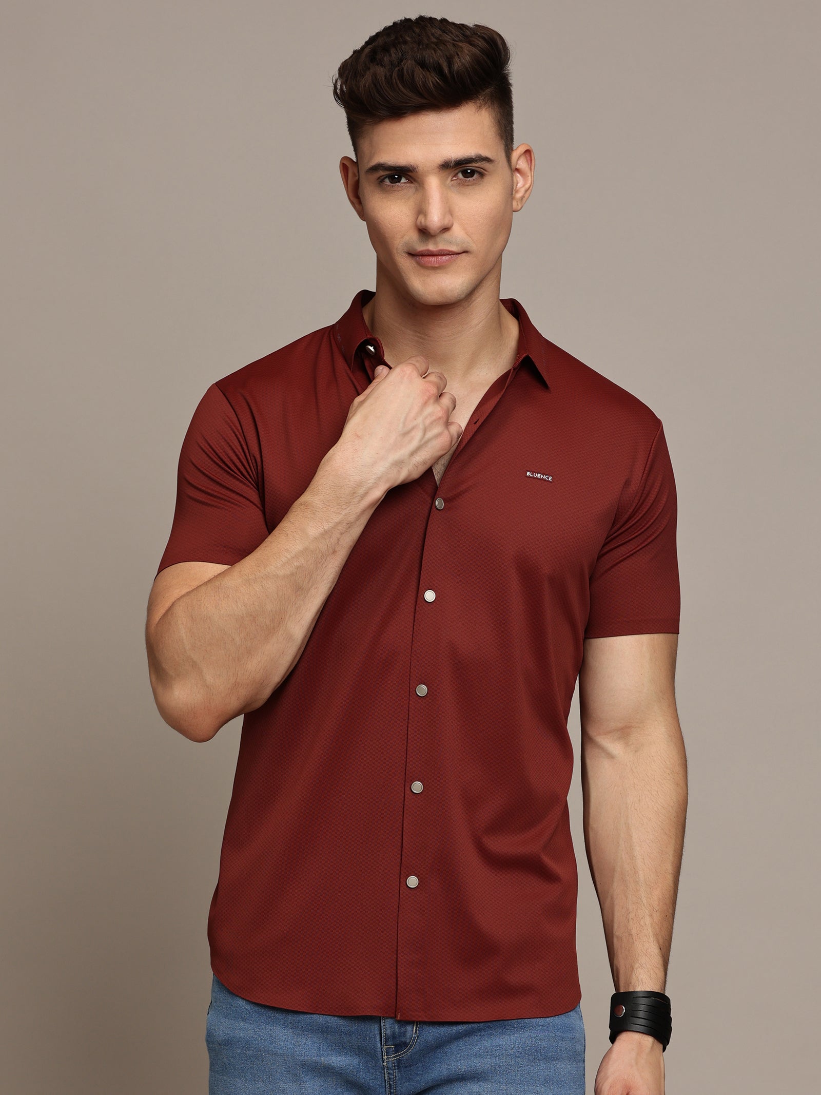 A male model wearing a brown, short-sleeved, button-up shirt.