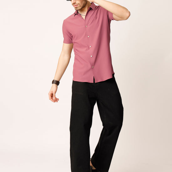 Man wearing a pink shirt and black pants against a white background