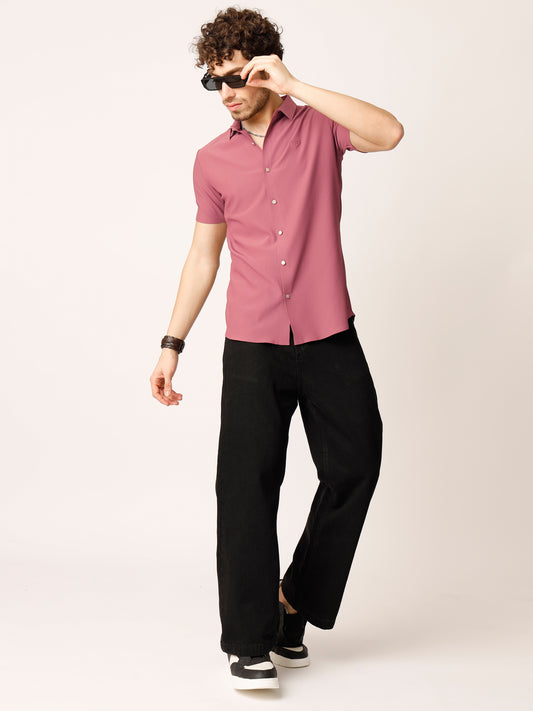 Man wearing a pink shirt and black pants against a white background