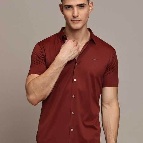 A male model wearing a brown, short-sleeved, button-up shirt.