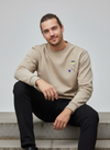 Man wearing a beige full-sleeves sweatshirt with embroidered designs 